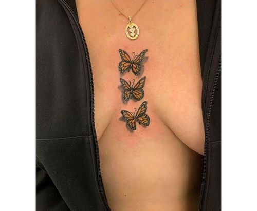 Black butterfly tattoo between breast