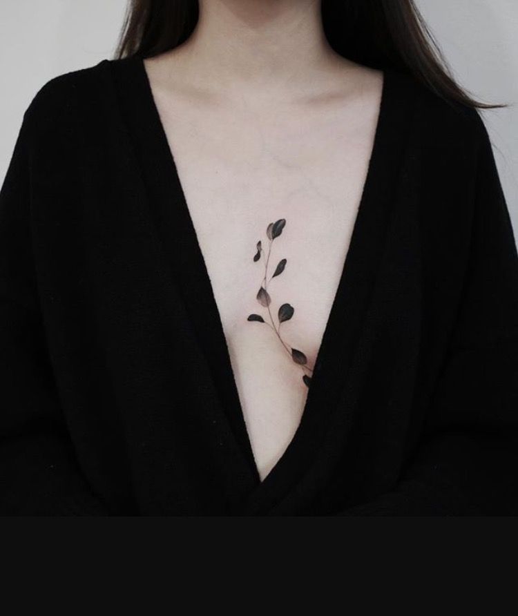 Small leaves in between breast tattoo